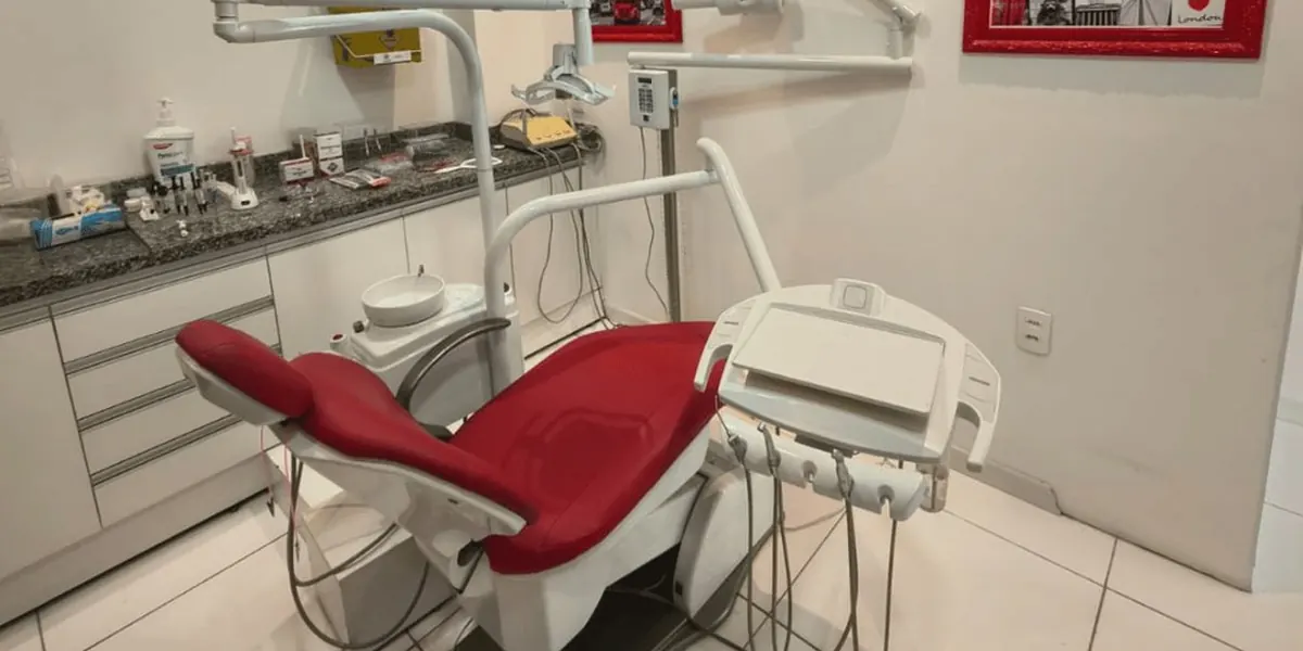 O consultório da OrtoDoctor São José, com a cadeira odontológica vermelha e os quadros de Londres na parede
