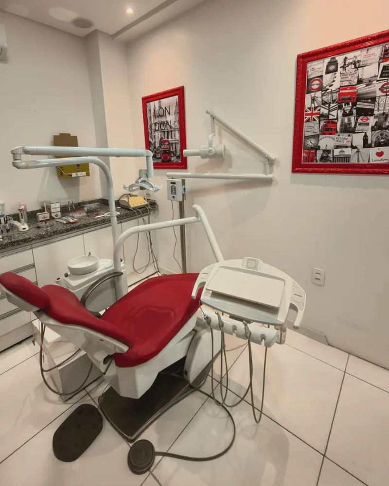 O consultório da OrtoDoctor São José, com a cadeira odontológica vermelha e os quadros de Londres na parede